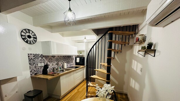 A modern kitchen with a wooden island, a black clock, and a staircase with wooden steps. - T2 Duplex in hyper-centre - Quiet, independent access (Vienne)