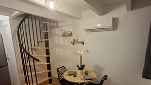 A compact kitchen with a wooden staircase, a dining table with chairs, and a hanging light fixture. - T2 Duplex in hyper-centre - Quiet, independent access (Vienne)