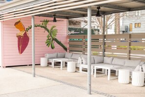 A covered outdoor seating area with a mural, a sofa set, and a 'Welcome to' sign. - 2BR Home | Grill + Free Parking | Near Beach + DT (North Charleston)