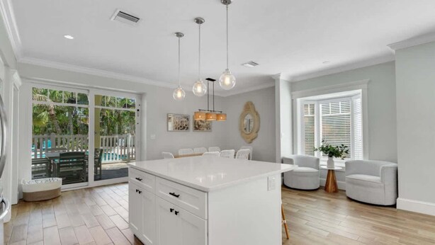 A spacious kitchen with a large island, white cabinetry, and pendant lighting. - The Pool House~Steps to Beach & Siesta Key Village (Siesta Key)