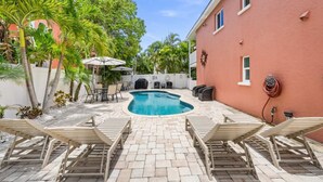 A swimming pool with lounge chairs, a barbecue area, and outdoor seating. - Summer Salt – Steps to Siesta Key Village & Beach (Siesta Key)
