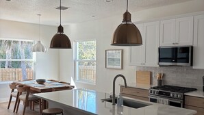 Una cocina moderna con una isla grande, luces colgantes y vistas al exterior.