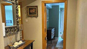 A hallway with a wooden console table, a mirror, a framed picture, and a rug. - Corraleith/Cozy 2 Bedroom/2 Bath Leith Flat: Tram at Ocean Terminal: Parking (Edinburgh)