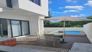 Eine moderne Außenpatio mit Pool, einem Tisch mit Stühlen und einem großen Sonnenschirm.