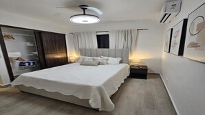 Ein Schlafzimmer mit einem Bett, Nachttischen, einem Kleiderschrank und einem Deckenventilator.