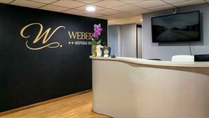 A reception desk with a black wall featuring a gold monogram and the name 'WEBER HOSPITAL.' - Hospedaje Boutique Weber's (Gijón)