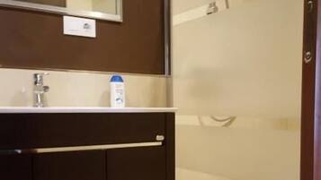 Un baño moderno con tocador de madera oscura, un espejo y zona de ducha.