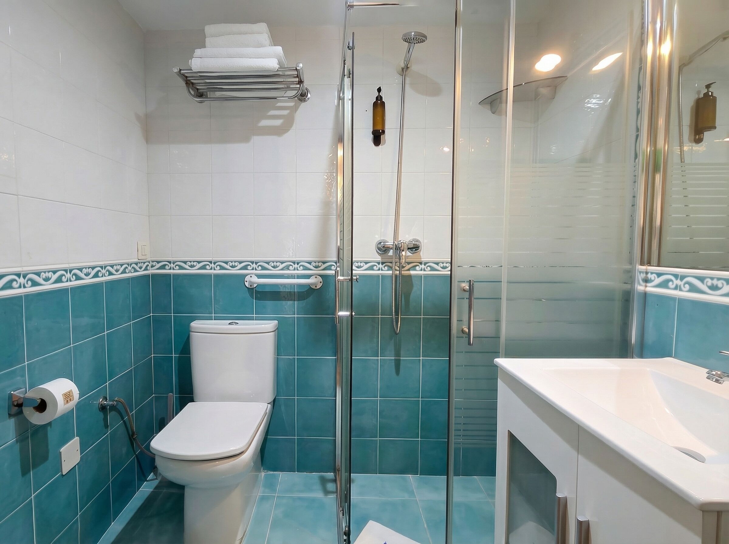 A bathroom with a toilet, a glass-enclosed shower, and a sink.