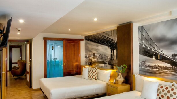A hotel room with two beds, a shower, a view of a bridge, and a cityscape. - Hospedaje Boutique Weber's (Gijón)