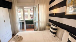 A hotel room with a bed, a nightstand, a window with curtains, and a view of the outside. - Hospedaje Boutique Weber's (Gijón)