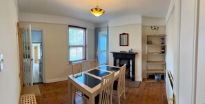 A dining area with a glass-top table and chairs, a fireplace, and a bookshelf. - 4 Bed Private Victorian Town House - Central Headington - Oxford (Oxford)