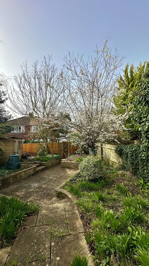 A garden with a paved pathway, flowering trees, and a wooden fence. - 4 Bed Private Victorian Town House - Central Headington - Oxford (Oxford)