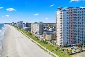 A beachfront hotel with multiple high-rise buildings, a sandy beach, and a swimming pool area. - The Palace Resort #1114 (Myrtle Beach)