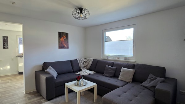 A modern living room with a dark grey sectional sofa, a small white coffee table, and a unique black spherical light fixture.