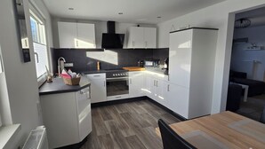 A modern kitchen with white cabinets, a black stove, and a microwave.