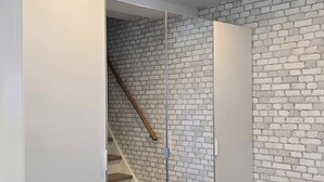 A modern room with a wooden staircase, white brick wall, and a large wardrobe with mirrored doors.