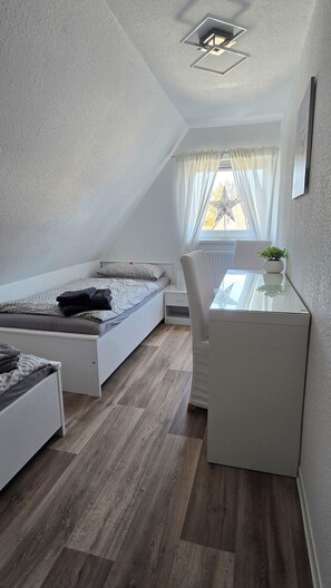 Una habitación pequeña con cama, escritorio y silla.
