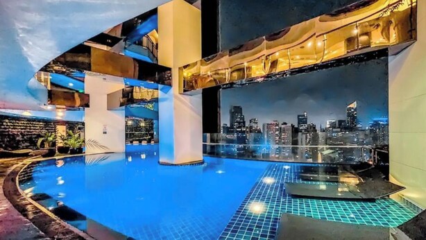 Una piscina interior moderna con vistas a la ciudad, que presenta un diseño arquitectónico geométrico y una barrera de vidrio.
