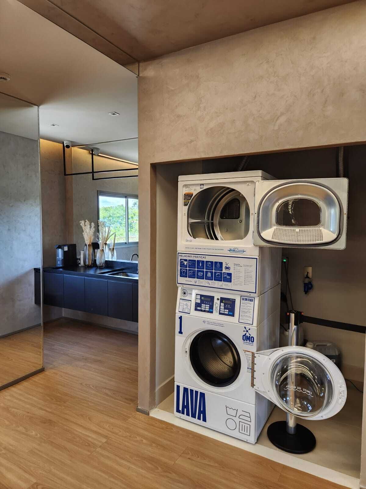 Una cucina moderna con lavatrice e asciugatrice integrate, pavimento in legno e una finestra che lascia entrare luce naturale.