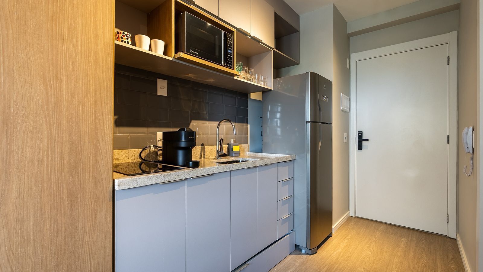 A compact kitchen with a built-in microwave, coffee maker, and refrigerator.