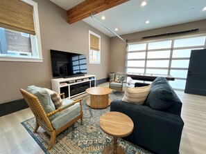 A living room with a television, sofa, chair, and a large window. - 2 Villas • Sleeps 21 • Theater • Sauna • Hot Tubs (Ocean Shores)