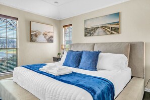 A bedroom with a large bed, a headboard, and two windows. - Spacious Gem, Hot Tub, 10 Min to AT&T & DFW | JCE (Grand Prairie)