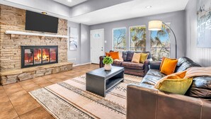 Ein modernes Wohnzimmer mit Kamin aus Stein, Ledersofas und großen Fenstern.