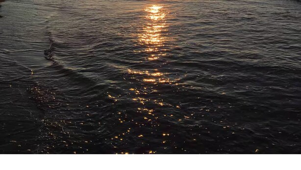 A sunset over a beach with waves reflecting the sun. - Spacious Country Home 10 minutes from Cavendish (Lot 20)