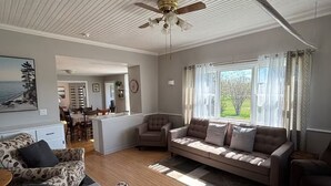 A spacious living room with a sofa, a patterned armchair, and a ceiling fan. - Spacious Country Home 10 minutes from Cavendish (Lot 20)