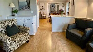 A living room with a sofa, a coffee table, and a dining area with chairs and a table. - Spacious Country Home 10 minutes from Cavendish (Lot 20)
