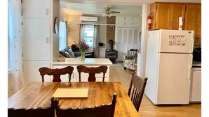 A dining area with a wooden table and chairs, a white refrigerator, and a kitchen area with wooden cabinets and a stove. - Spacious Country Home 10 minutes from Cavendish (Lot 20)