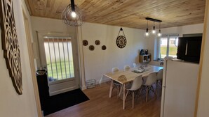 A dining area with a wooden table and chairs, a television, and a window with a view of the outdoors. - The House of Mountains (Le Thillot)