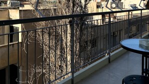 A balcony with a view of buildings and a tree. - The Temple of Comfort (Athina)