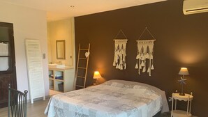 Une chambre à coucher avec un lit, des lampes de chevet, une commode, un miroir, une échelle et des éléments de décoration murale.