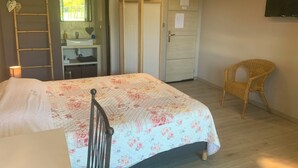 Une chambre à coucher comprenant un lit, une chaise, une armoire, un miroir et un téléviseur.