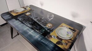 A dining table with a cityscape design, two plates, cutlery, and wine glasses. - Harmony Living-Theatro Massimo Studio- City Center (Catania)