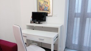 A white desk with a computer monitor, a chair, and a painting on the wall. - Harmony Living-Theatro Massimo Studio- City Center (Catania)