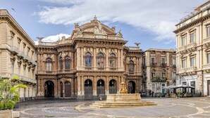 A historic building with ornate architecture, a central courtyard, and a fountain. - Harmony Living-Theatro Massimo Studio- City Center (Catania)