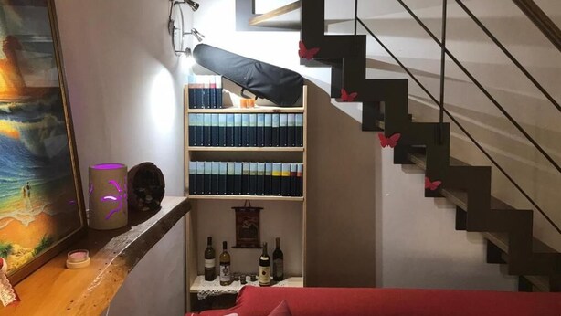 A staircase with a modern design, a bookshelf with books, and a painting on the wall. - B&B Il Dolce Dormire offers comfort and style in one. (Ponte Valleceppi)