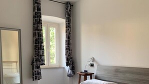A bedroom with a bed, a window with curtains, a bedside table with a lamp, and a mirror on the wall. - B&B Il Dolce Dormire offers comfort and style in one. (Ponte Valleceppi)