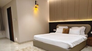 A modern bedroom with a large bed, a headboard with built-in lighting, and a neutral color scheme. - THE CROWN TOWN BIDAR (Bidar)