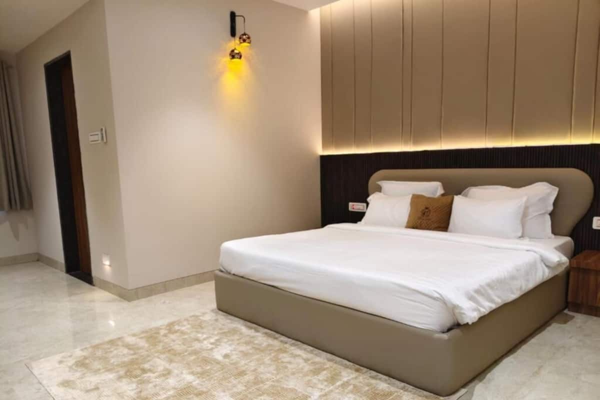 Ein modernes Schlafzimmer mit einem großen Bett, einem Kopfteil mit integrierter Beleuchtung und einer neutralen Farbgestaltung.