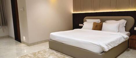 Un dormitorio moderno con una cama grande, cabecera con iluminación integrada y una paleta de colores neutros.
