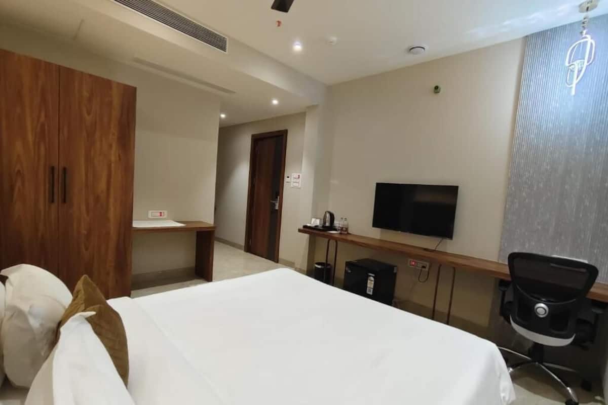 Ein Hotelzimmer mit einem Bett, einem Schreibtisch mit Fernseher, einem Sessel und einem Kleiderschrank.