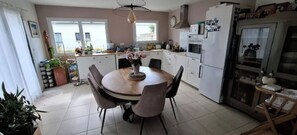 Eine moderne Küche mit weißen Schränken, einem Esstisch mit Stühlen und einem Kühlschrank.