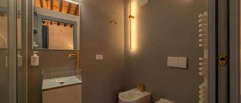 Un baño moderno con cabina de ducha de vidrio, un bidé y un inodoro.