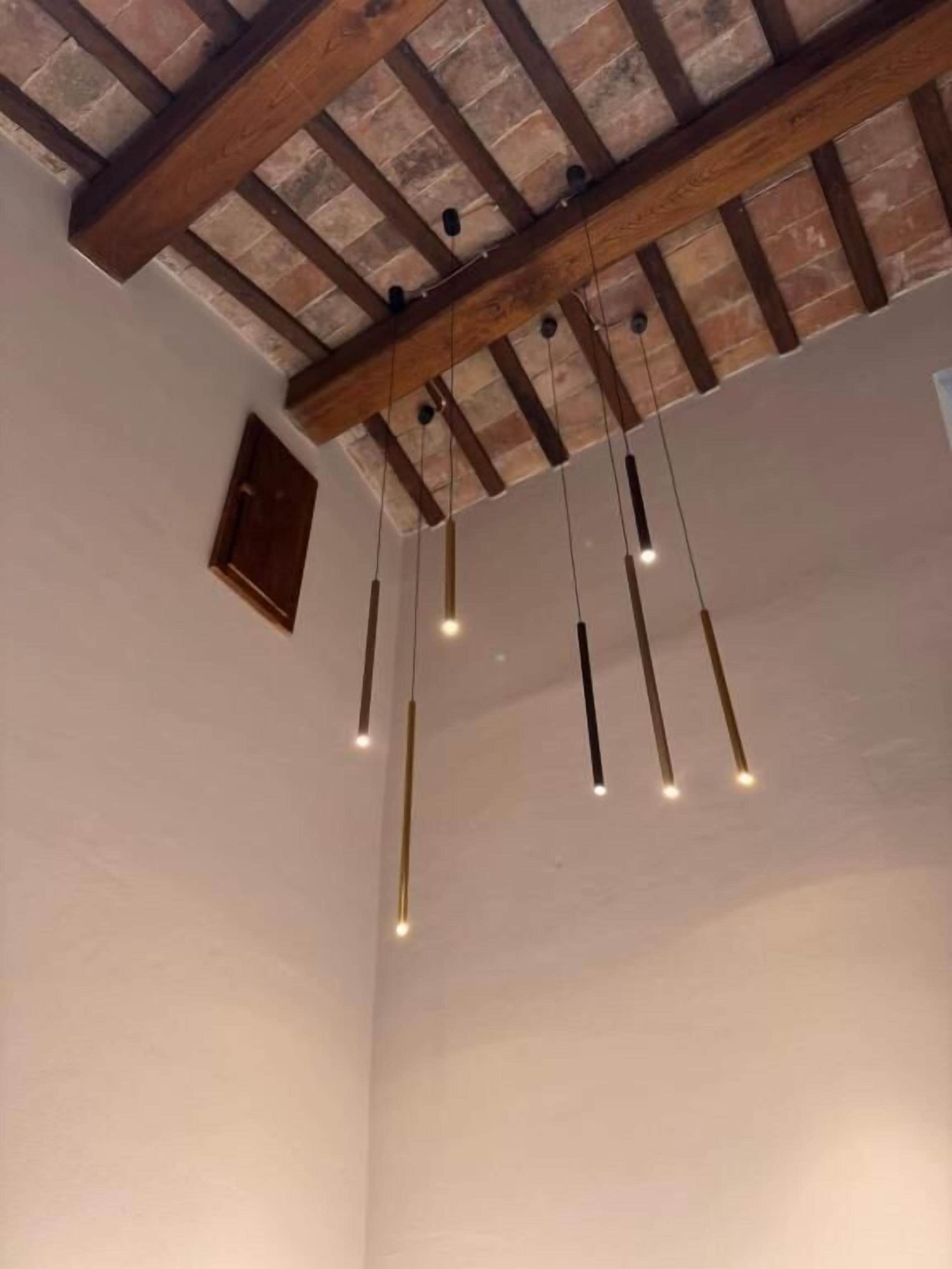 Une pièce avec des poutres apparentes et des luminaires suspendus.