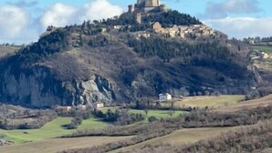 A hilltop castle with a prominent tower, surrounded by rolling hills and sparse vegetation. - Maison Ventiquattro Suite & Spa (Talamello)