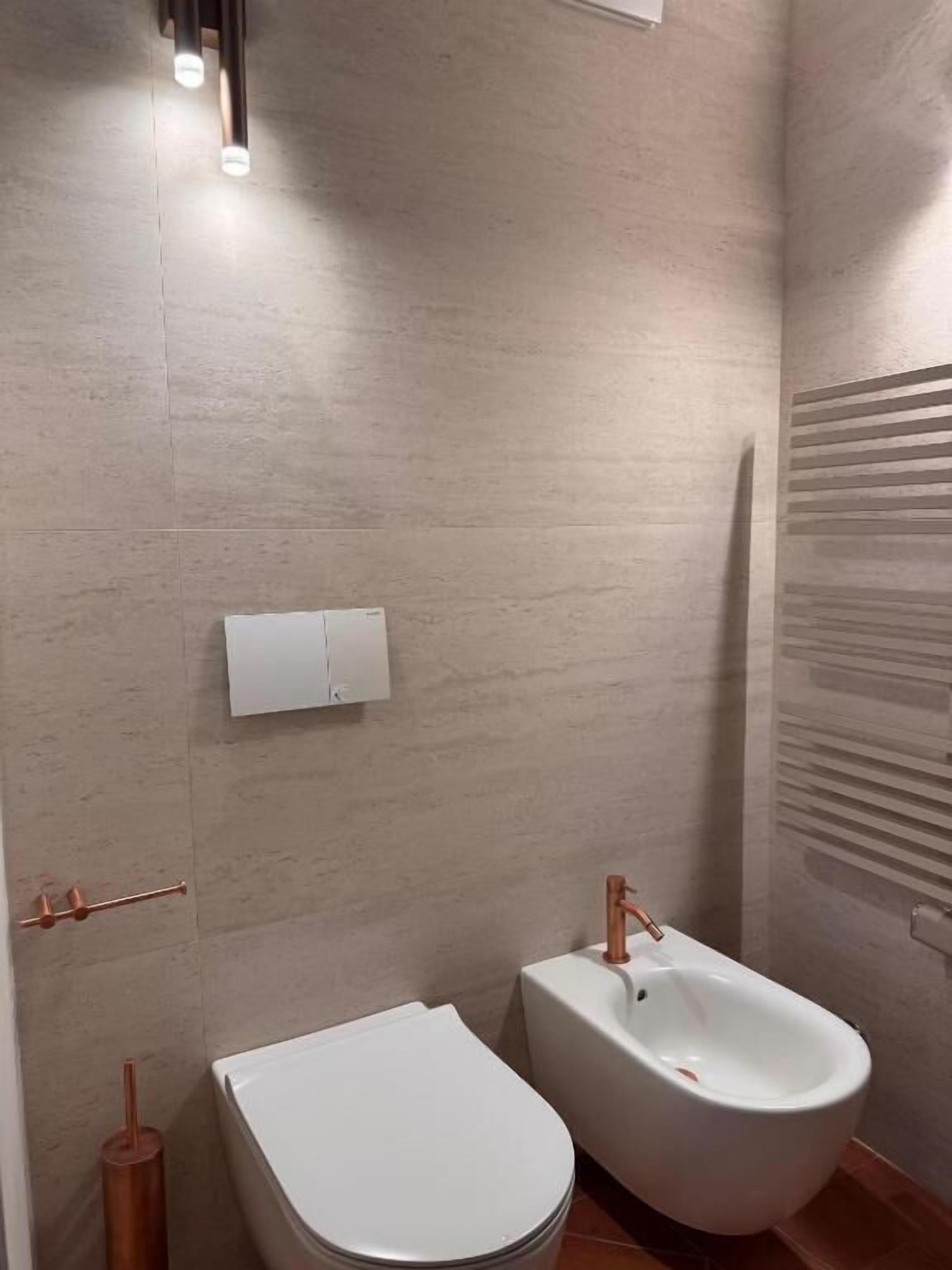 Un bagno moderno con un WC, un bidet e un porta asciugamani.