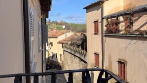 A narrow cobblestone street with buildings on either side, a balcony with a wrought iron railing, and a clear blue sky. - Maison Ventiquattro Suite & Spa (Talamello)